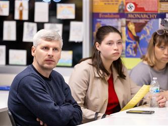 A student and their family are seen listening to the speaker