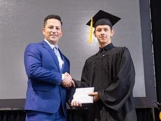 Principal posing with graduating senior