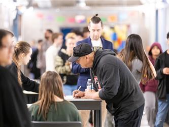 An adult is signing a paper at a students display table