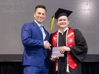 Principal posing with graduating senior